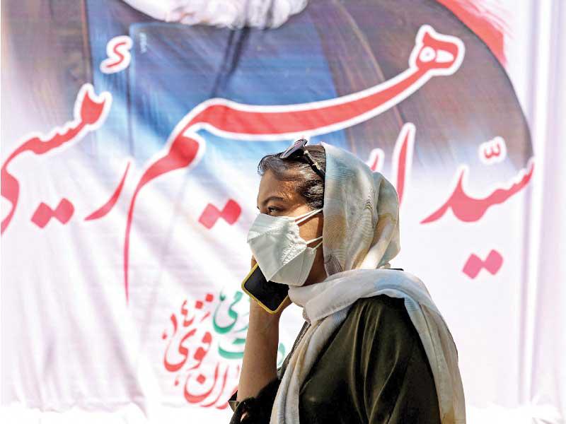 إيرانية تمر بجوار صورة للمرشح الرئاسي رئيسي في طهران الجمعة الماضية  (أ ف ب)