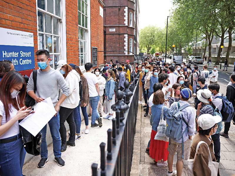 شباب ينتظرون دورهم للحصول على التطعيم ضد «كورونا» في لندن أمس   (رويترز) 