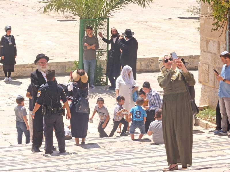 فلسطينية تلتقط صورة «سيلفي» قرب مستوطنين دخلو الحرم القدسي بحراسة الشرطة أمس     (أ ف ب)