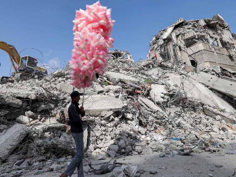 فتى فلسطيني يبيع حلوى قطنية في غزة قرب مبان دمرت في آخر عملية إسرائيلية ضد القطاع (أ ف ب )