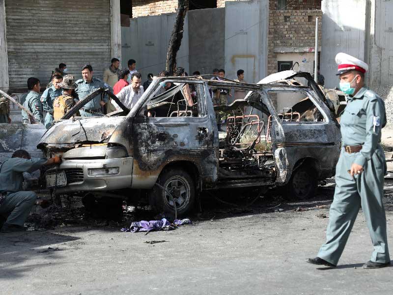 عناصر أمن يعاينون حطام سيارة ركاب بعد تعرّضها للتفجير في كابول أمس (رويترز)