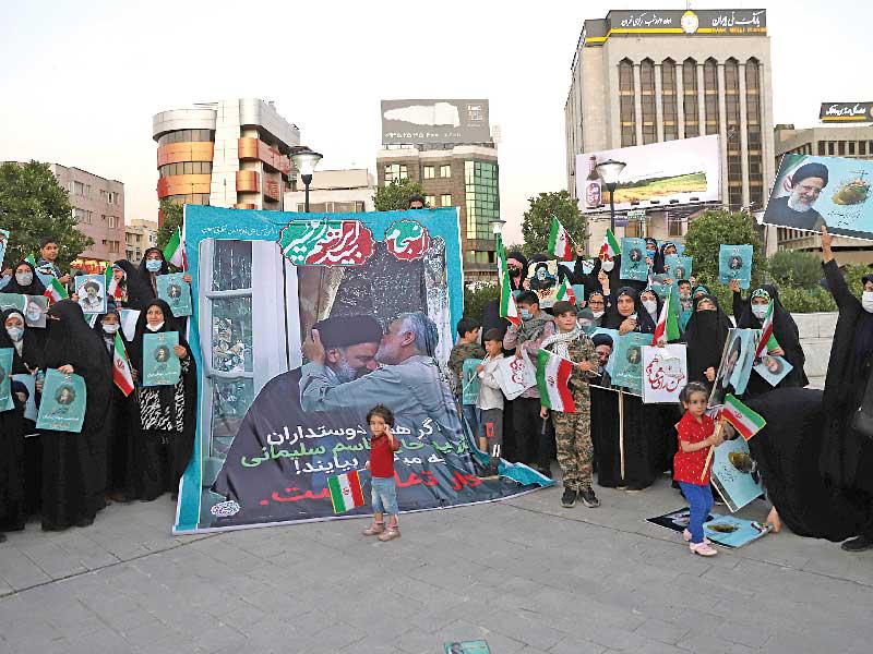 مؤيديو رئيسي يرفعون صورته مع قاسم سليماني في طهران أمس الأول (رويترز)