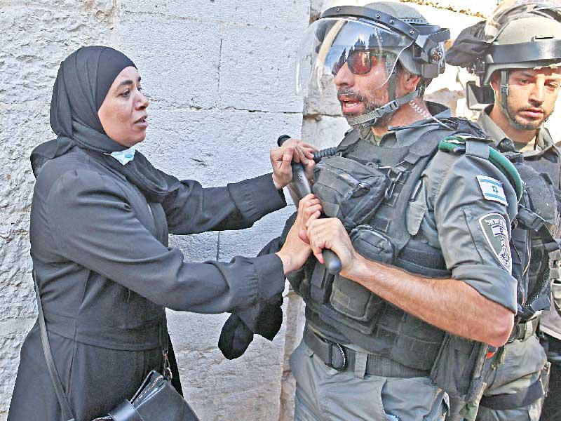 فلسطينية تتصدى لشرطي إسرائيلي عند بوابة دمشق في القدس القديمة امس (أ ف ب)