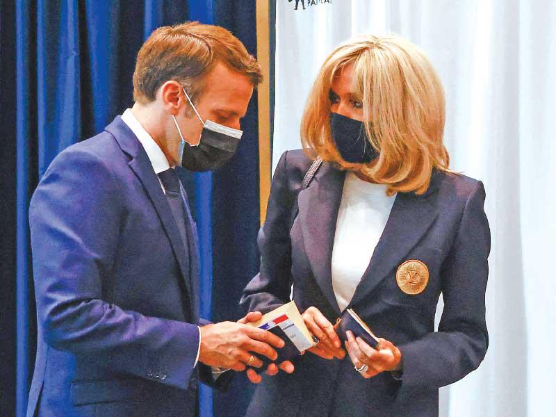 الرئيس الفرنسي إيمانويل ماكرون وزوجته بريجيت بعد الإدلاء بصوتيهما في منطقة لو توكيه أمس (ا ف ب)