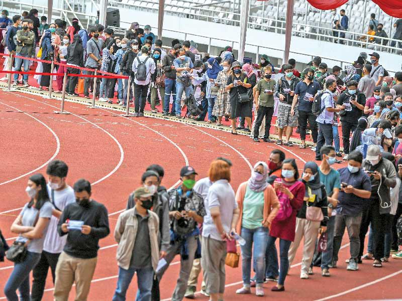 إندونيسيون يصطفّون بطابور طويل في ملعب بانتظار حصولهم على التطعيم أمس (رويترز)