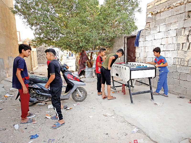 فتية عراقيون يلهون في شارع ببغداد (رويترز)