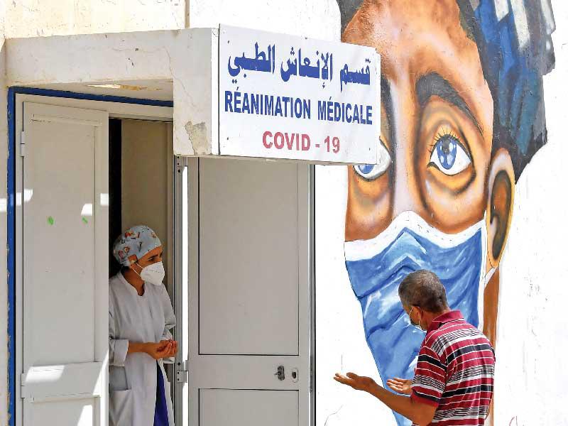 طبيب تونسي يتحدث مع والد أحد مرضى «كورونا» في مستشفى ابن الجزار في مدينة القيروان أمس    (أ ف ب)