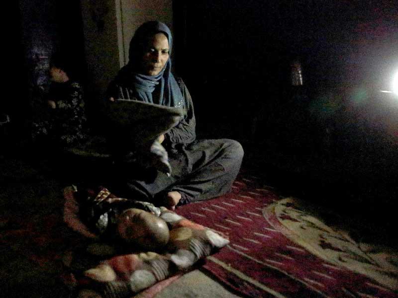 امرأة عراقية تجلس بجانب طفلها في منزلها أثناء انقطاع التيار الكهربائي في بغداد