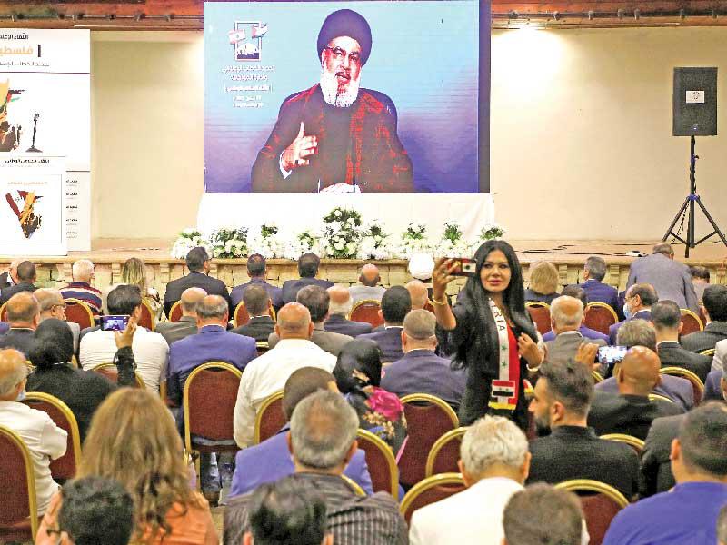 لبنانية تلتقط سيلفي مع نصرالله الذي يحدث انصاره عبر شاشة عملاقة في بيروت أمس (رويترز)