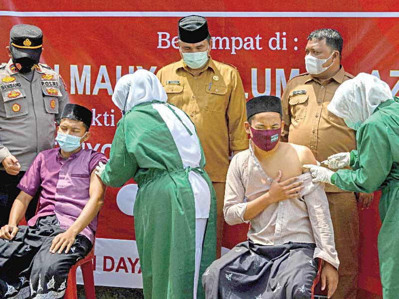 طلاب يتلقّون لقاحاً ضد «كورونا» في إحدى مدارس إندونيسيا أمس               (أ ف ب)