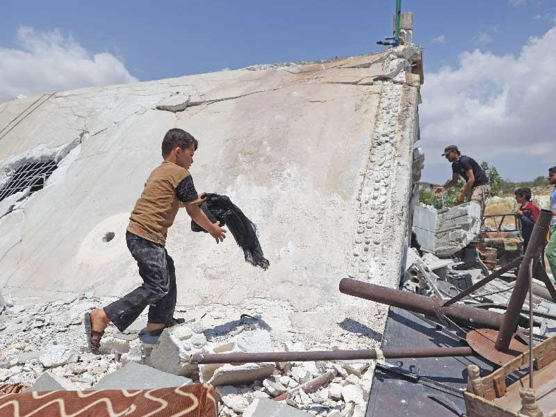 صبي سوري يستخرج متعلقاته من منزل عائلته المدمر في هجوم صاروخي روسي على منطقة جبل الزاوية جنوب إدلب أمس الأول                  (أ ف ب)