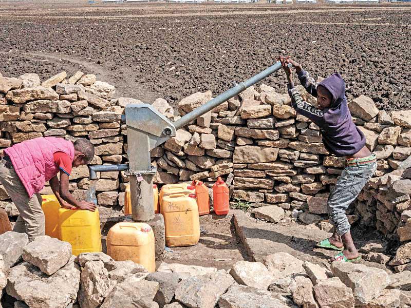 إثيوبيان يتزودان بالمياه من بئر في أرض زراعية بتيغراي (أ ف ب)