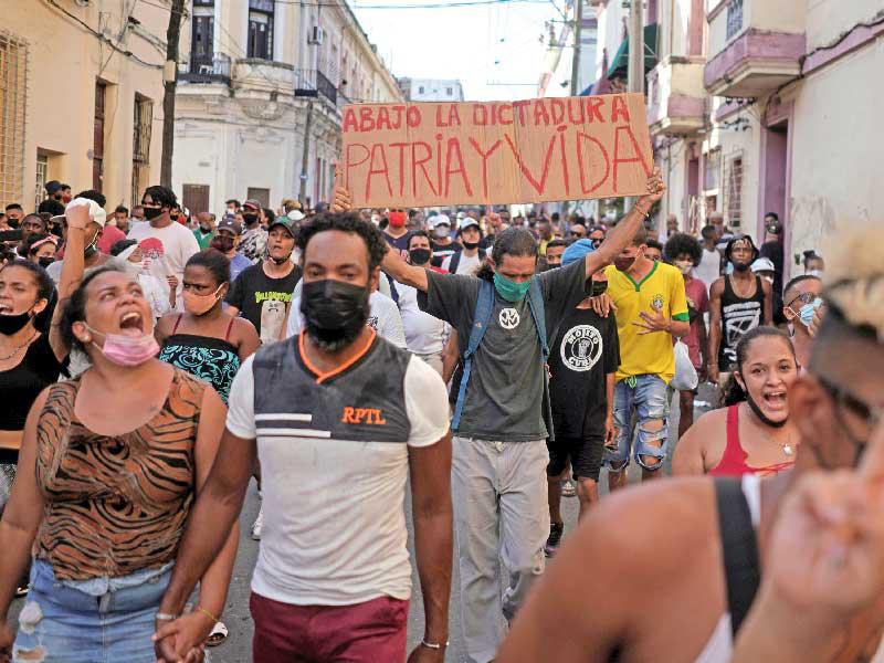 معارضون يرفع أحدهم لافتة كتب عليها «تسقط الدكتاتورية يعيش الوطن» في هافانا أمس الأول (رويترز)  