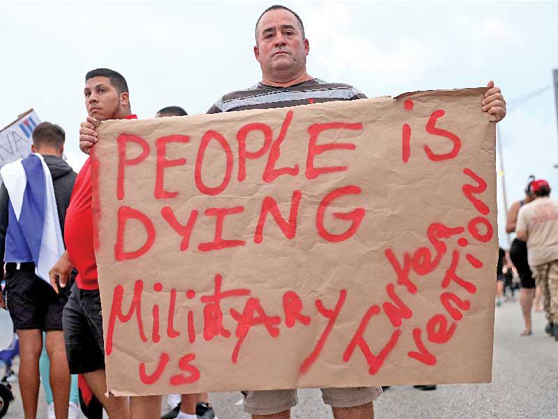 متظاهر في ميامي حيث تعيش جالية كوبية كبيرة يحمل لافتة تدعو إلى تدخل عسكري أميركي في كوبا (أ ف ب)