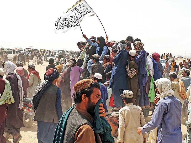 باكستانيون يلوحون أمس برايات «طالبان» عبر الحدود بعد سيطرة الحركة على معبر بين البلدين (أ ف ب)n