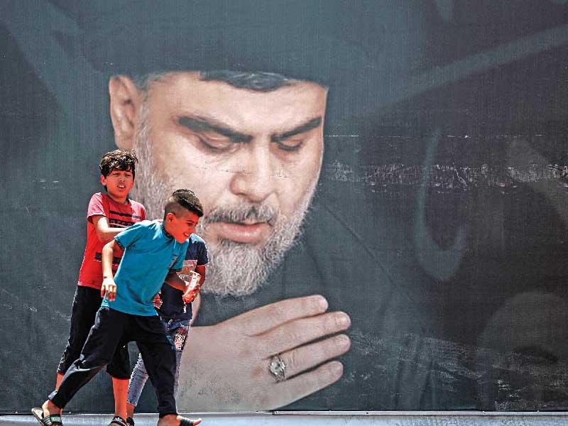 فتيان عراقيان يمران امام صورة كبيرة للصدر في مدينة الصدر شرق بغداد أمس (أ ف ب)