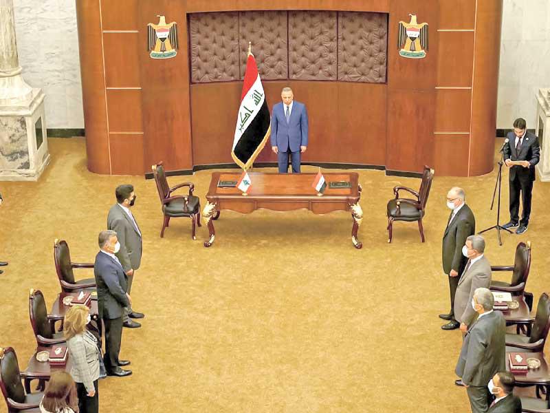 الكاظمي متوسطاً الوفدين العراقي واللبناني خلال التوقيع على الاتفاقيةt(أ ف ب)