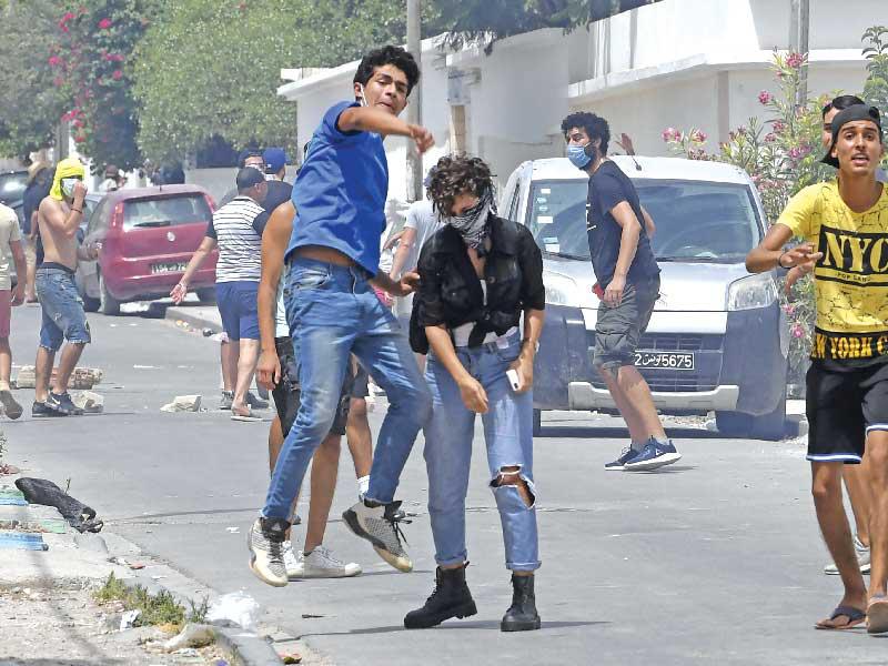 متظاهرون يرشقون الشرطة بالحجارة في العاصمة التونسية أمس (أ ف ب)