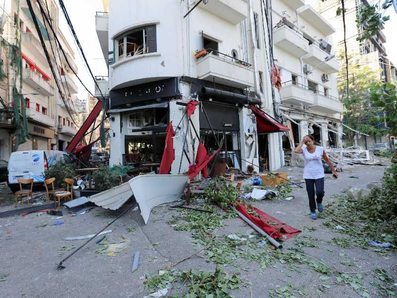 امرأة تمر أمام مطعم متضرر في أعقاب انفجار 4 أغسطس في ميناء بيروت ، لبنان