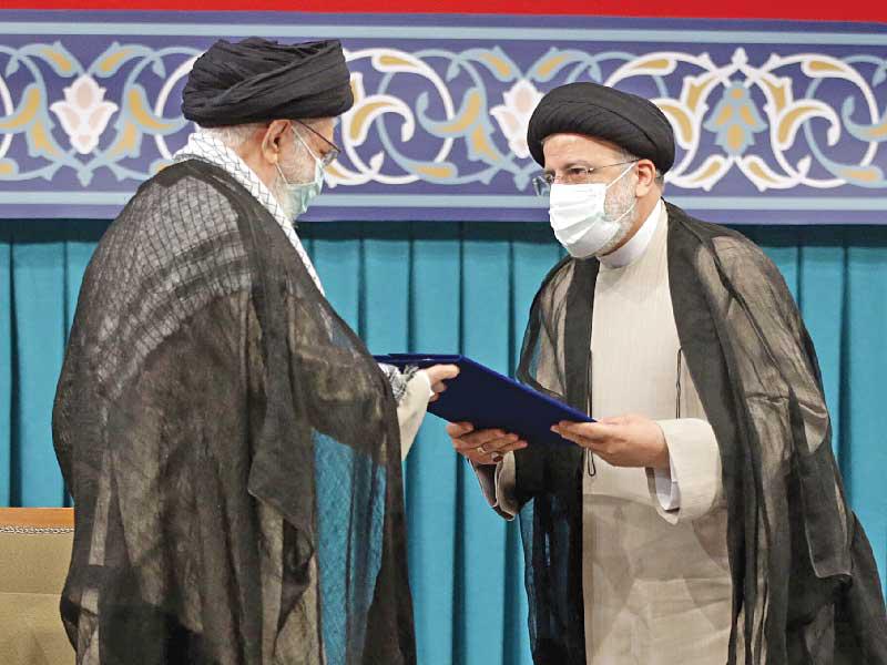 خامنئي يسلم إلى رئيسي كتاب نقل السلطة بطهران أمس (رويترز)n