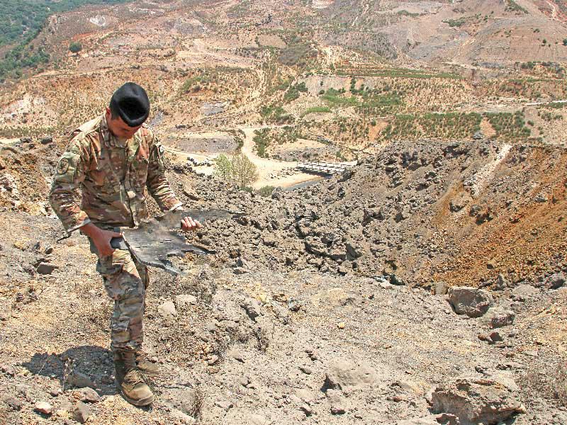 جندي لبناني يحمل بقايا قذيفة إسرائيلية في منطقة مرجعيون الجنوبية أمس (رويترز)