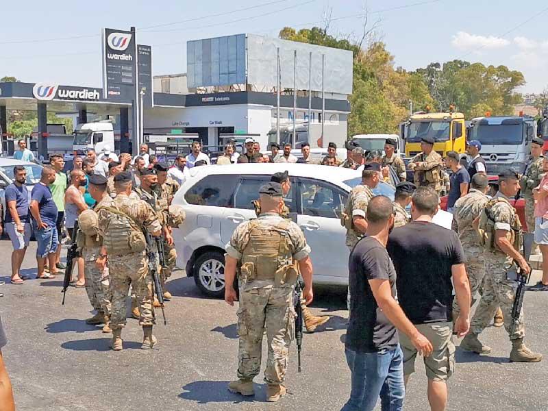 جنود لبنانيون يحاولون فتح طريق قطعها محتجّون أمام محطة وقود في مدينة صيدا أمس (رويترز)
