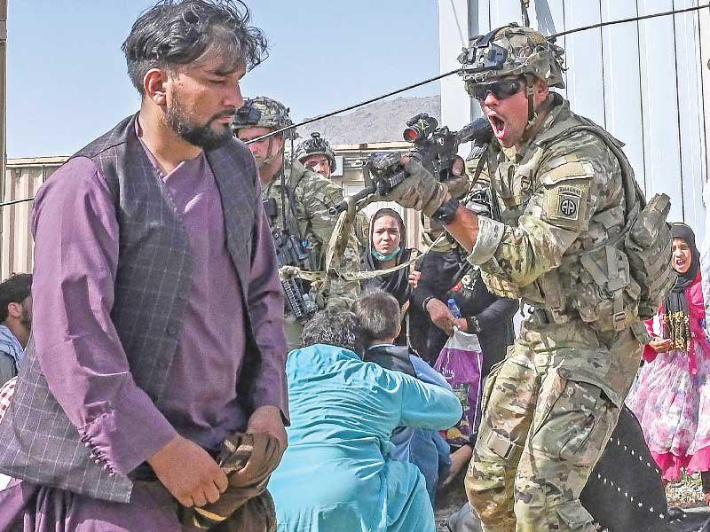 جندي أميركي يوجه بندقيته لمسافر أفغاني في مطار كابول أمس	 (أ ف ب)