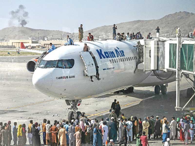 عدد من الافغان الحاربين يلتمون حول طائرة في مطار كابول 