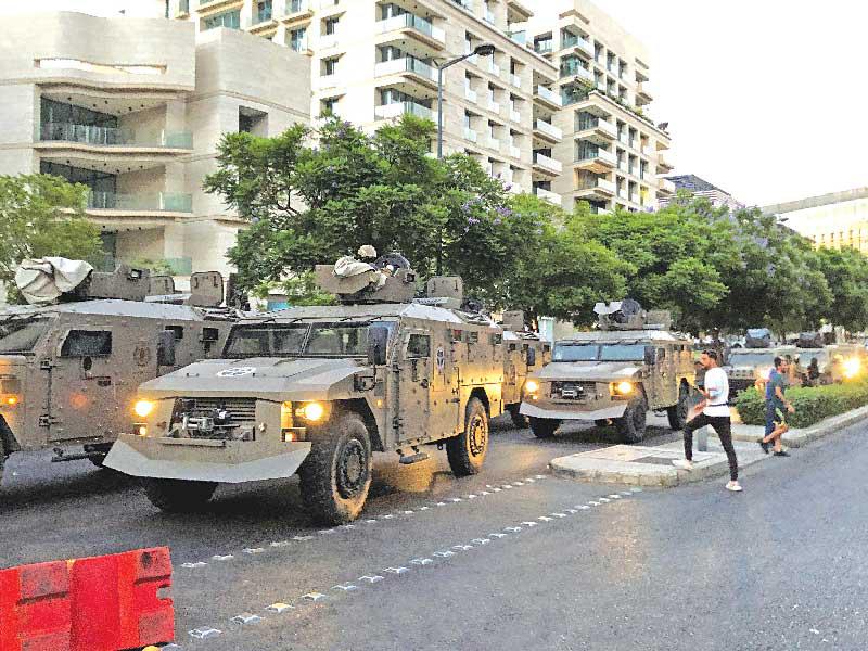 سيارات عسكرية تغادر بعد مواجهات مع متظاهرين قرب منزل ميقاتي في بيروت أمس الأول (رويترز)