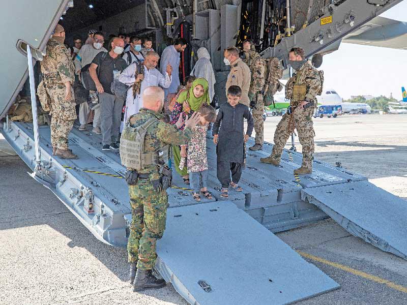 جنود ألمان يستقبلون مدنيين أفغاناً بمطار أوزبكستان أمس (رويترز)