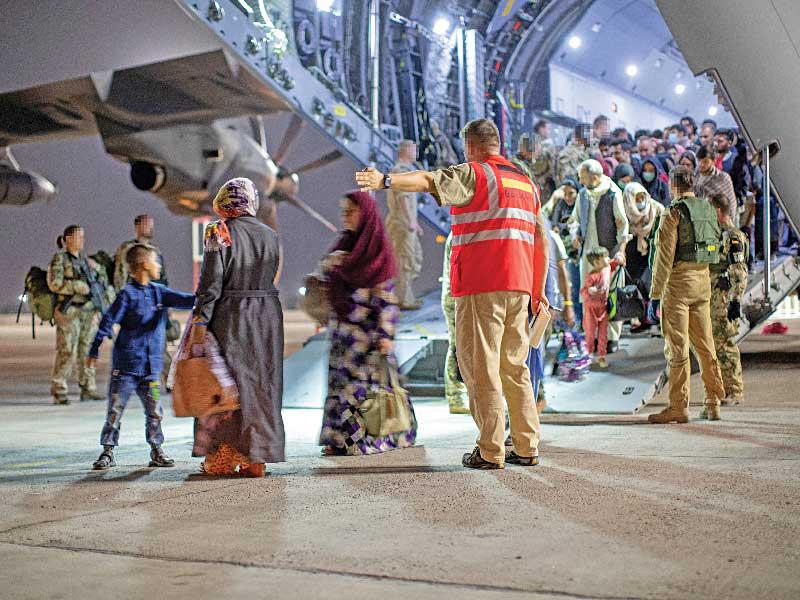 جنود ألمان يساعدون على إنزال مدنيين أفغان لدى وصولهم إلى أوزبكستان مساء امس الأول (رويترز) 