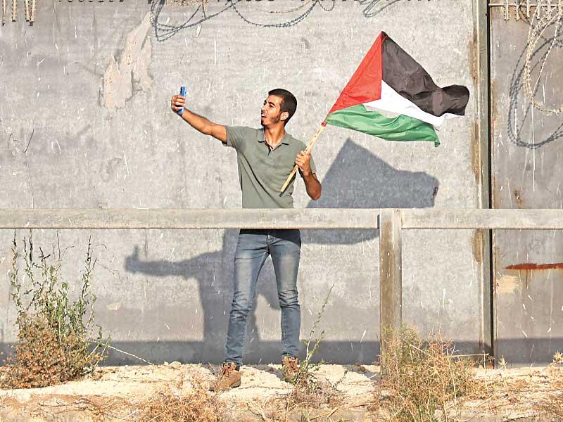 فلسطيني يلتقط سيلفي قرب الجدار الحدودي بين غزة وإسرائيل أمس الأول (أ ف ب)