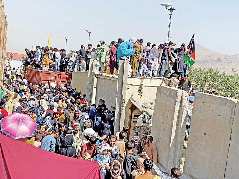 أفغان يتسلّقون أحد أسوار مطار كابول أمس (رويترز)