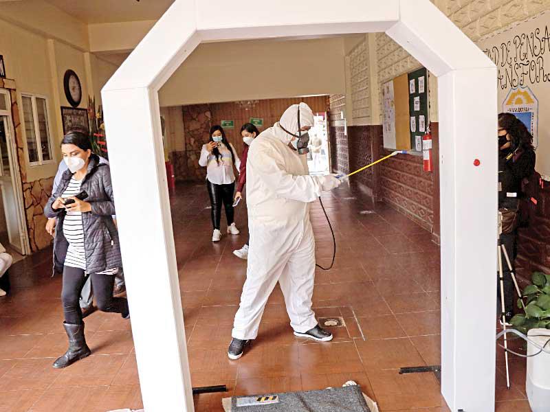 عامل يعقّم مدخل إحدى المدارس استعداداً لإعادة فتح العام الدراسي وسط تفشي «كورونا» في مدينة إيكاتيبيك المكسيكية     (رويترز)