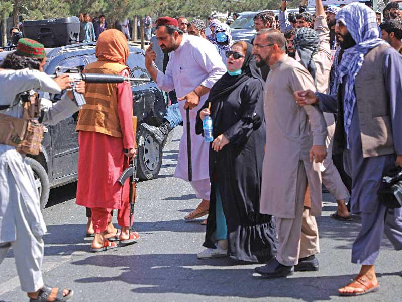  مسلّح من «طالبان» يشهر سلاحه بوجه متظاهرين سلميين في كابول أمس الأول (رويترز) 