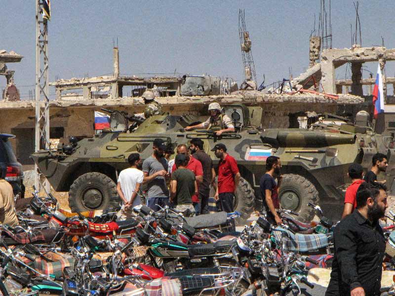 سوريون يتحدثون مع القوات الروسية التي انتشرت في درعا البلد أمس الأول (أ ف ب)