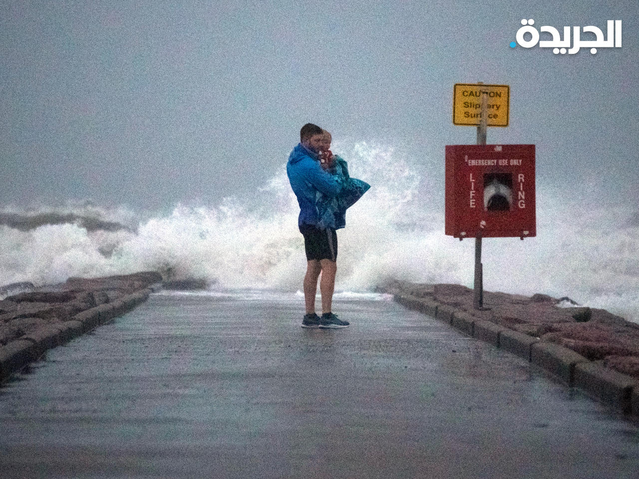 أمريكي يحمل ابنه قبل وصول العاصفة الاستوائية نيكولاس في تكساس