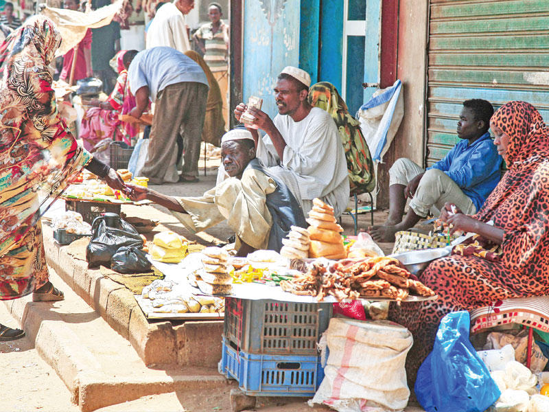 سيدة تشتري الخبز من أحد الأسواق المحلية في الخرطوم أمس (أ ف ب)