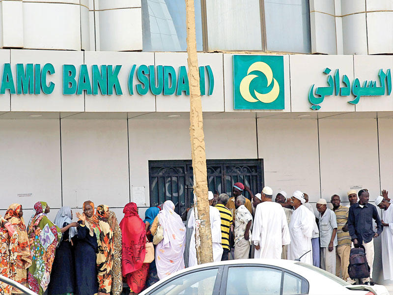 سودانيون ينتظرون أمام أحد المصارف في الخرطوم (رويترز)