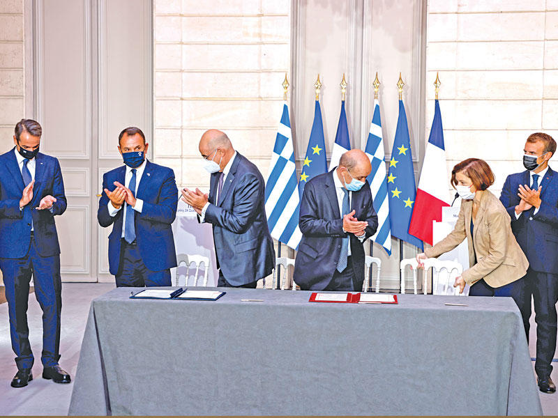 ماكرون وميتسوتاكيس يصفقان عقب توقيع الجانبين الفرنسي واليوناني صفقة الفرقاطات في الإيليزيه أمس (أ ف ب)n