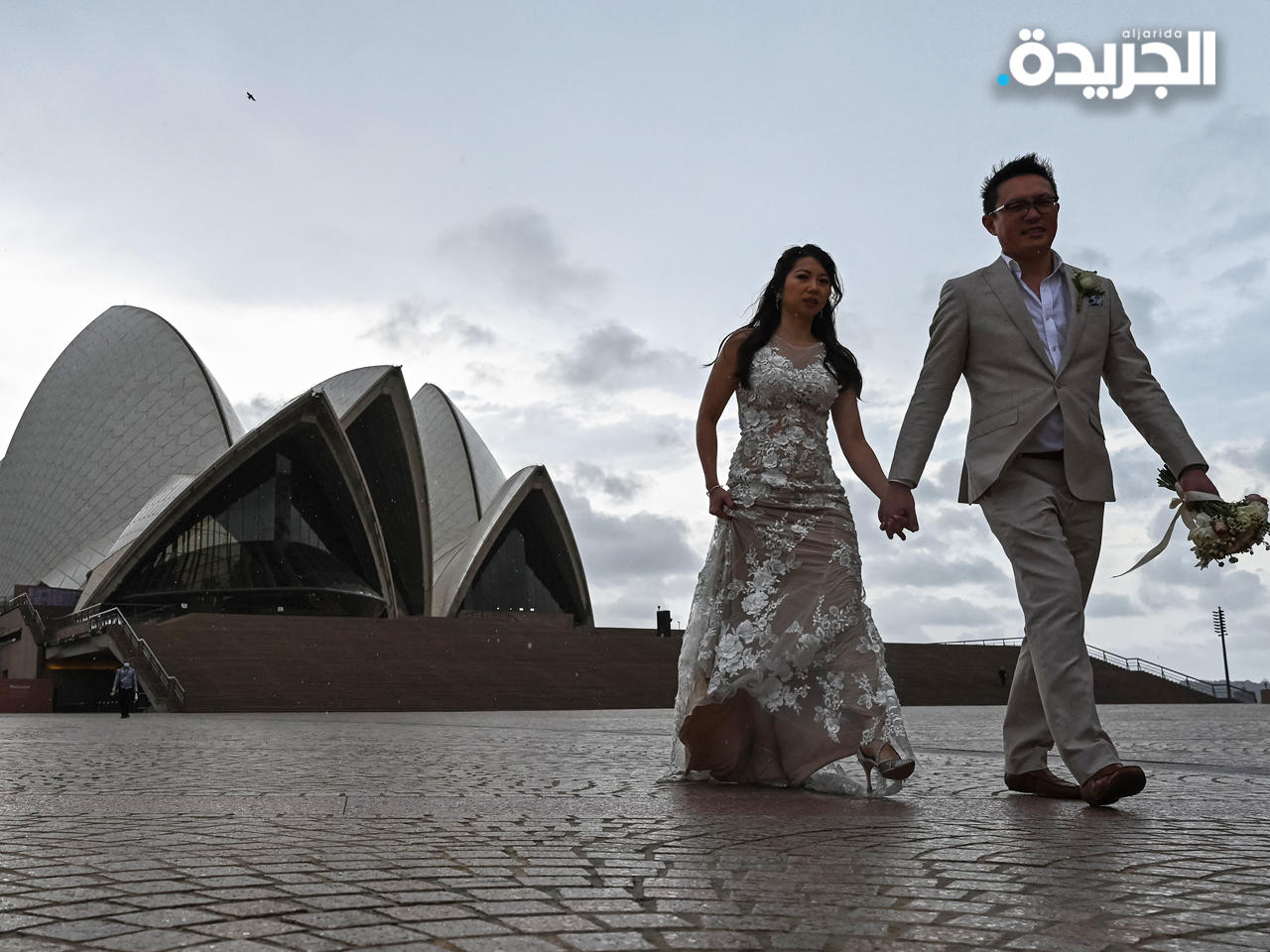 عريسان يلتقطان صور زفافهما بجوار دار أوبرا سيدني