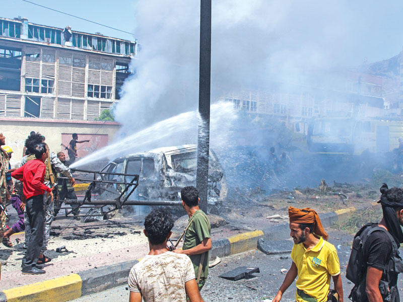 قوات الدفاع المدني وعناصر أمنية بموقع الاعتداء في عدن أمس (رويترز)n