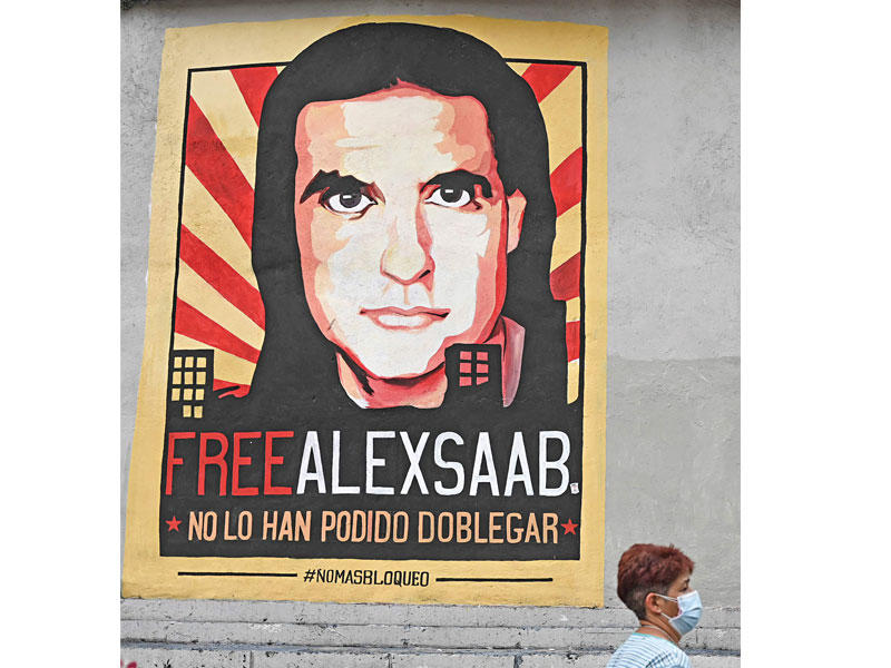 سيدة تمرّ أمام صورة لصعب تطالب باطلاقه في كراكاس (أ ف ب)