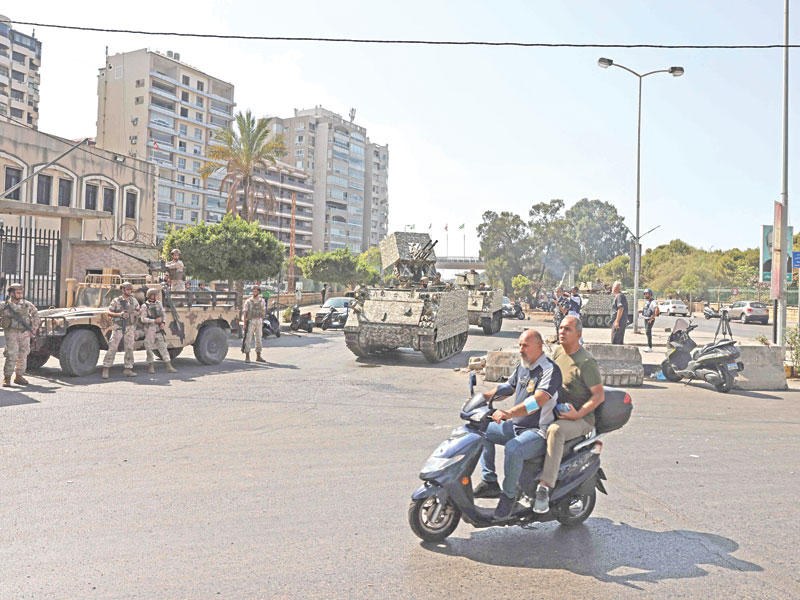 لبنانيان على دراجة نارية يعبران أمام قوة عسكرية في بيروت 	(أ ف ب)