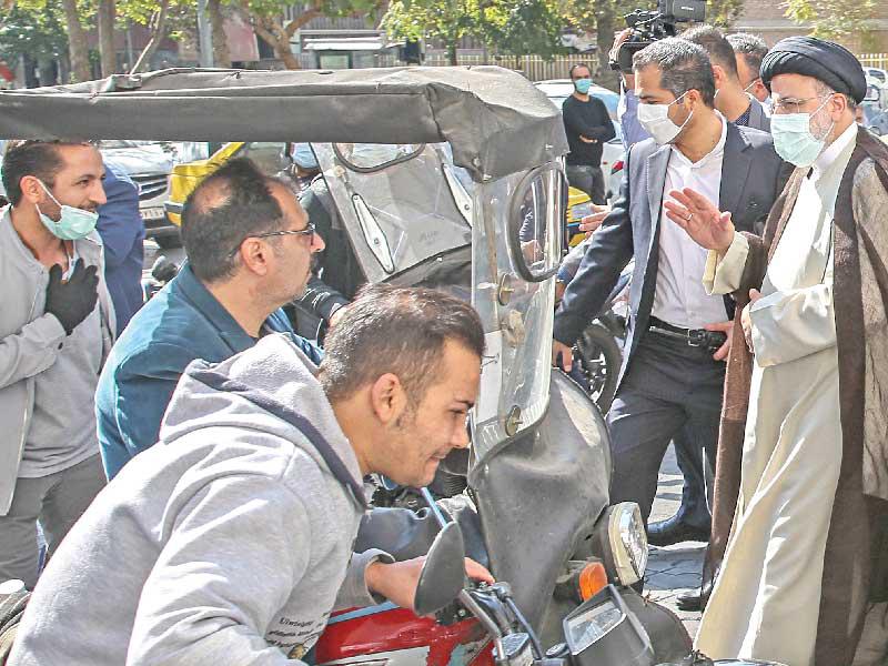  الرئيس الإيراني الأصولي إبراهيم رئيسي يلتقي إيرانيين أمام محطة بنزين وسط طهران أمس (د ب أ)