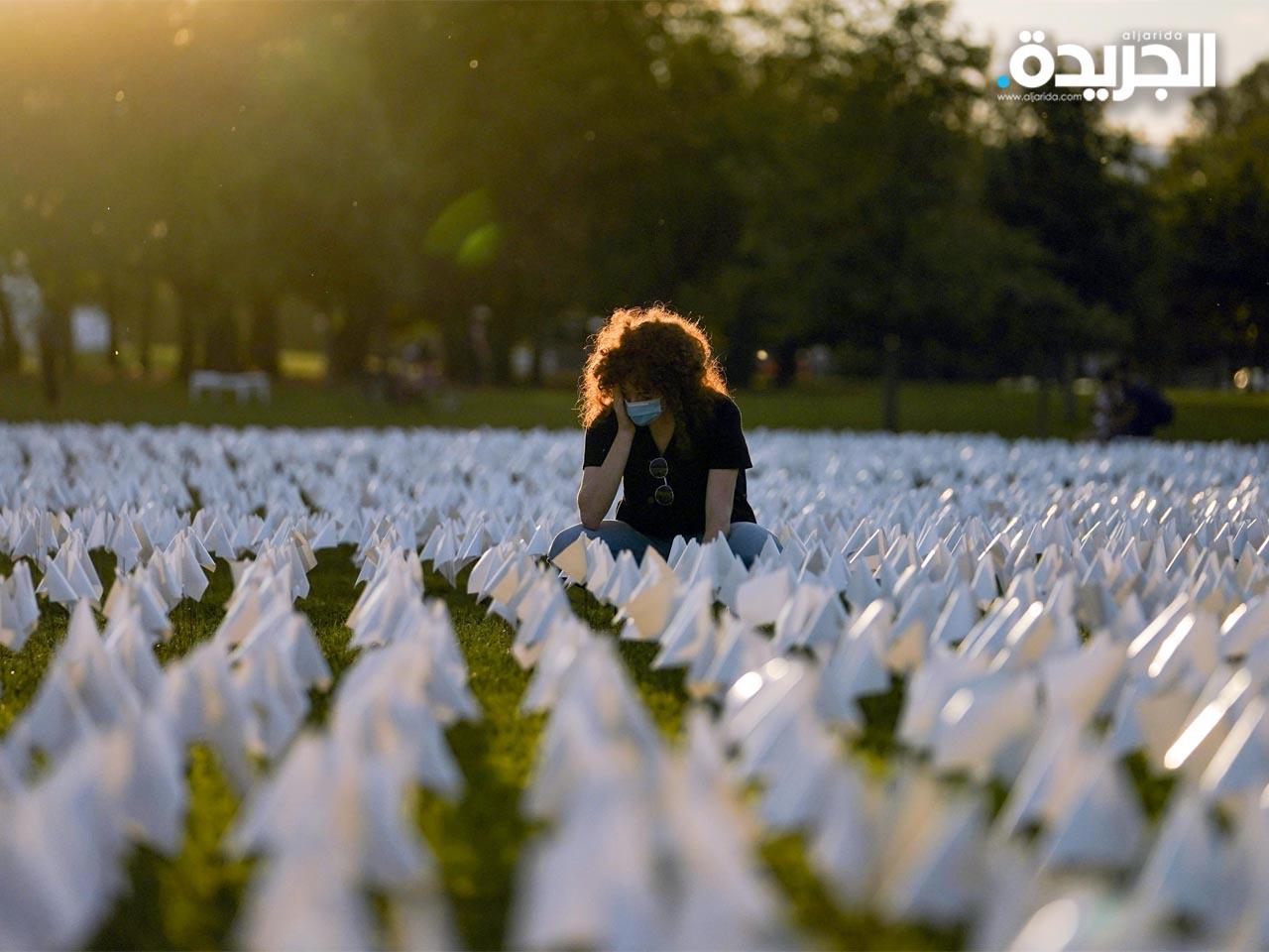 سيدة تجلس وسط عمل فني في واشنطن تخليداً لذكرى الأمريكيين الذين ماتوا بسبب كورونا