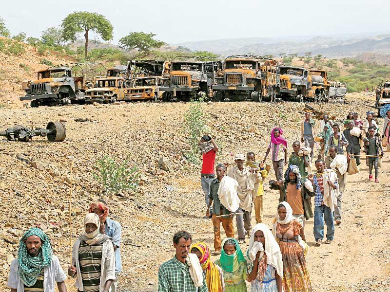 قرويون قرب آليات عسكرية دمرت خلال النزاع في إقليم تيغراي شمال إثيوبيا أكتوبر الماضي (رويترز)n