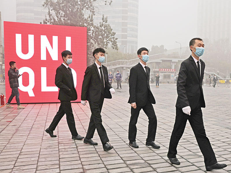 رجال أمن خارج متجر شهير للألبسة يفتتح فرعاً في بكين في «أجواء ملوثة» أمس      (رويترز)