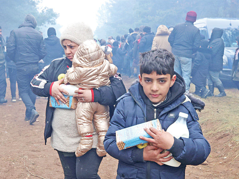 مهاجرون يصطفون للحصول على مساعدات عند الشريط الحدودي بين بيلاروس وبولندا أمس (رويترز)n