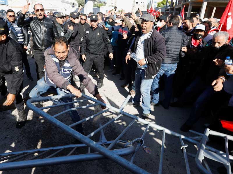 تونسيون يحاولون إزالة حواجز الشرطة للوصول إلى البرلمان أمس (رويترز)